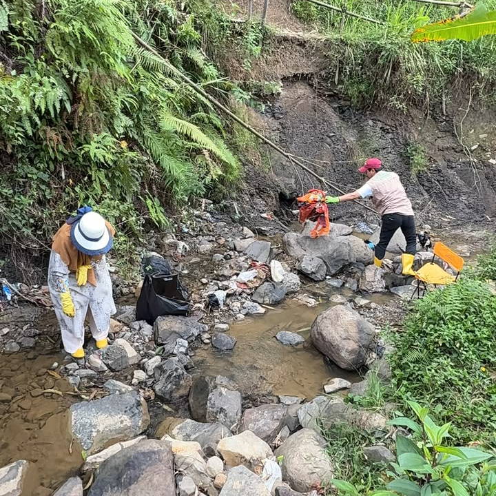 Dua warga memungut sampah di dasar sungai berbatu yang airnya tinggal sedikit