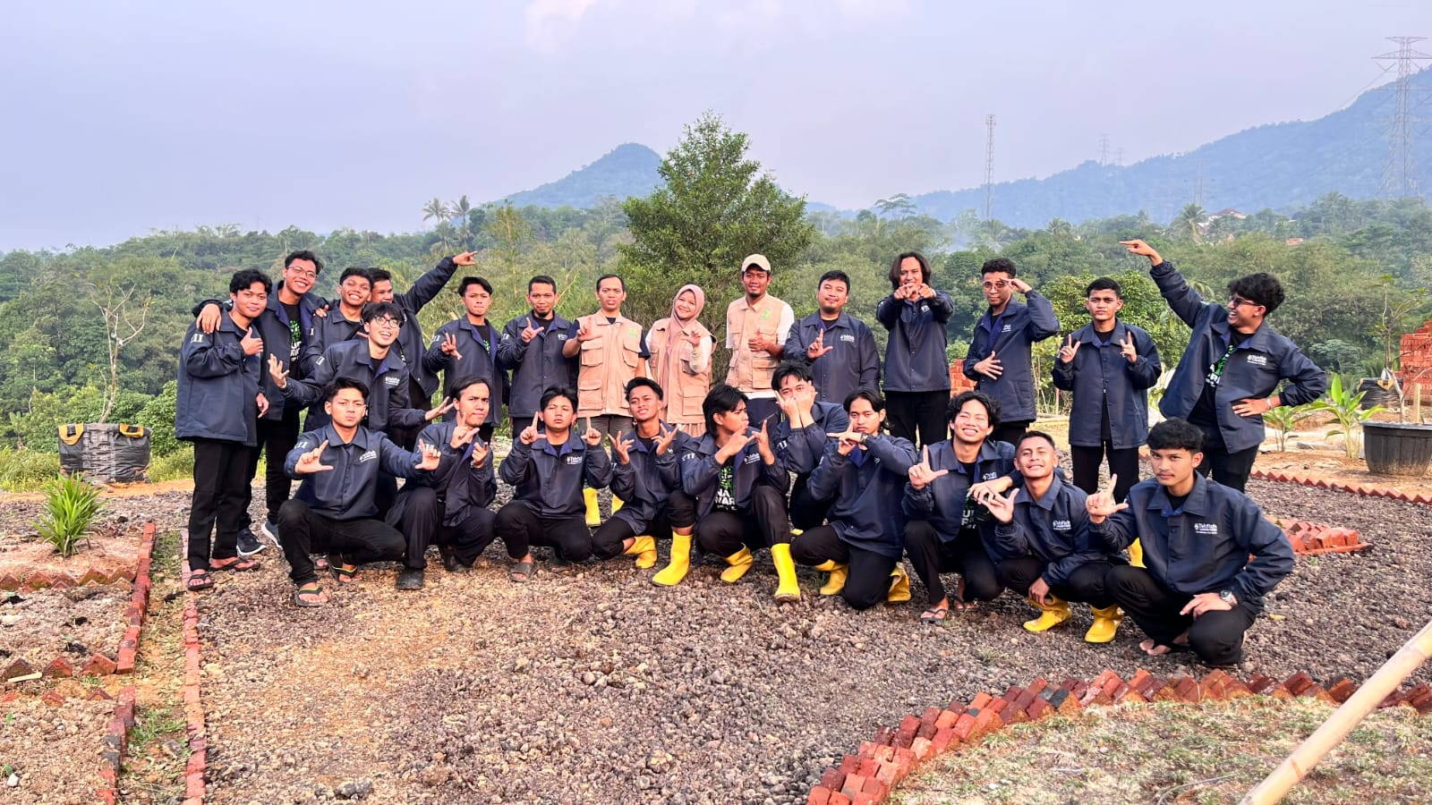 Puluhan santri berjaket biru tua berfoto bersama di lahan kawasan dengan latar perbukitan