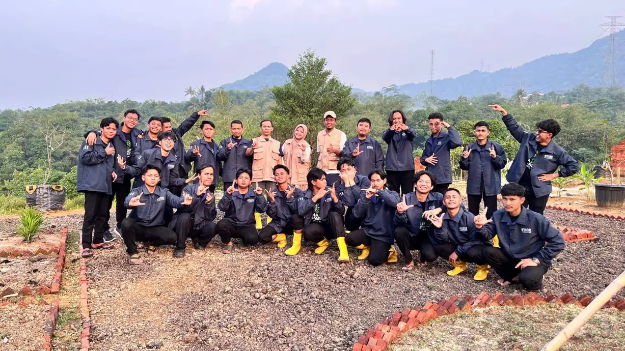 Puluhan santri berjaket biru tua berfoto bersama di lahan kawasan dengan latar perbukitan
